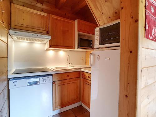 une cuisine avec des armoires en bois et un réfrigérateur blanc dans l'établissement Demi-chalet à La Clusaz, 6 pers, 3 ch, cheminée, parking, animaux ok - FR-1-818-27, à La Clusaz