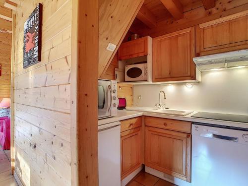 - une cuisine avec des placards en bois et un four micro-ondes dans l'établissement Chalet confortable 6 pers avec cheminée, WIFI, animaux admis, parking - La Clusaz - FR-1-818-71, à La Clusaz