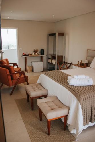 a bedroom with a large bed and a chair at ALDRAVA POUSADA BOUTIQUE in Tiradentes