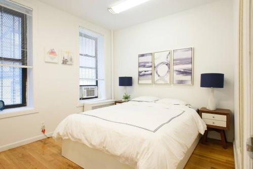 a white bedroom with a bed and two windows at 109-1 Huge 3BR Best Value - NYC Apt in New York