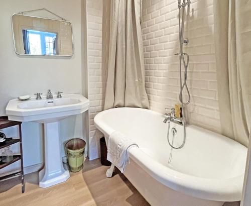 une salle de bain blanche avec une baignoire et un lavabo dans l'établissement Château de Vauville, à Vauville