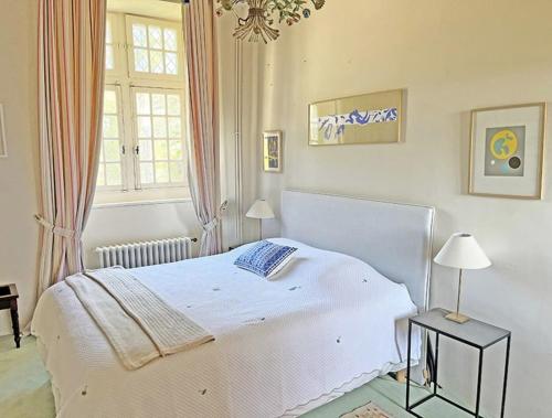 une chambre avec un lit blanc et une fenêtre dans l'établissement Château de Vauville, à Vauville