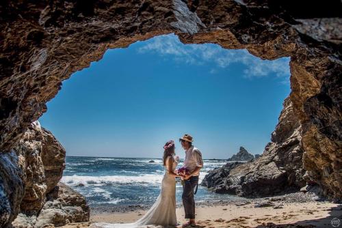 a bride and groom standing on the beach in front of a cave at ZOA Hotel - Adults Only in Mazunte