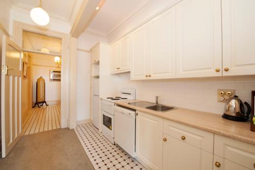 a kitchen with white cabinets and a sink at Cobb & Co Court Boutique Hotel in Mudgee