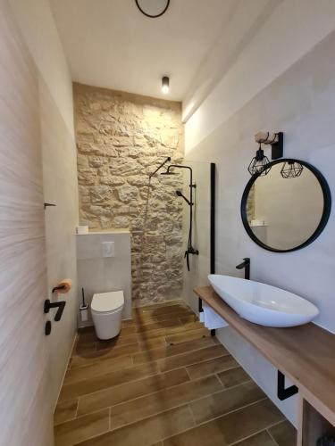 ein Badezimmer mit Waschbecken, Toilette und Spiegel in der Unterkunft Calico Apartment's in Jelsa
