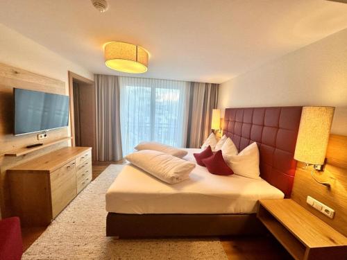 a hotel room with a bed and a television at Zirben Luxus Apartments mit SPA und Pool direkt in Kappl in Landeck