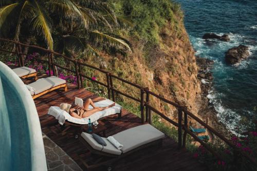 a woman laying on a deck next to the ocean at ZOA Hotel - Adults Only in Mazunte