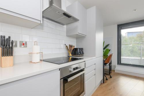 a white kitchen with a sink and a stove at Luxury Penthouse with Private Hot Tub Overlooking Leeds City Centre in Leeds