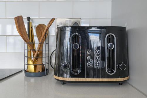 a black toaster sitting on a kitchen counter next to a vase of wood at Luxury Penthouse with Private Hot Tub Overlooking Leeds City Centre in Leeds