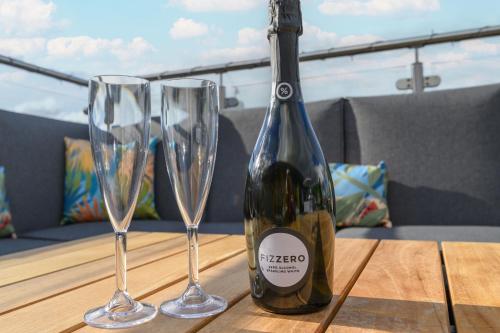 a bottle of wine and two wine glasses on a table at Luxury Penthouse with Private Hot Tub Overlooking Leeds City Centre in Leeds
