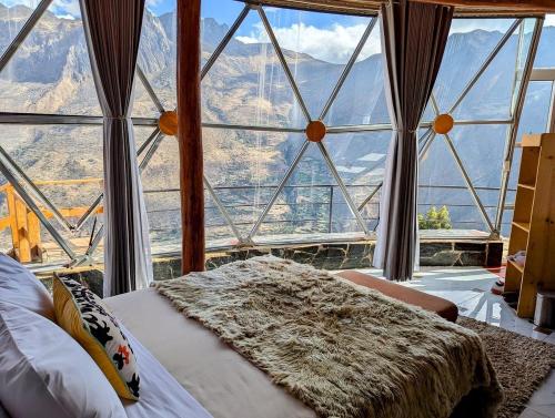 a bedroom with a large window with a view of mountains at Stardome Spiritual Experience in Ollantaytambo
