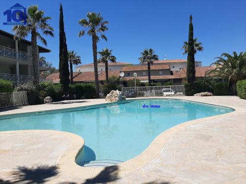 - une grande piscine dans un complexe avec des palmiers dans l'établissement Pavillon 300m Plage avec Piscine et Parking, Climatisation - FR-1-781-79, à Valras-Plage