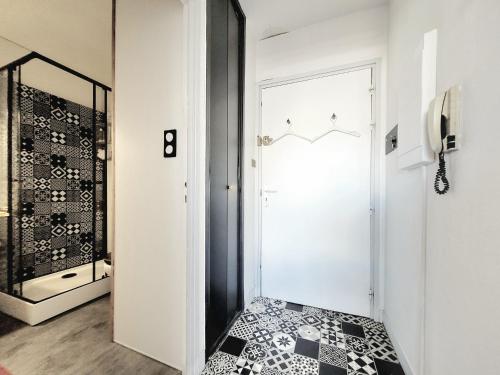 - un couloir avec une porte en verre et du carrelage noir et blanc dans l'établissement Studio rénové en bord de mer à Canet, proche commodités, idéal pour 3 personnes - FR-1-794-158, à Canet