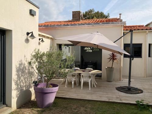 un patio avec un parasol, une table et des chaises dans l'établissement Maison rénovée avec jardin et terrasse au cœur de La Chaume, proche plage, WiFi - FR-1-92-944, à Les Sables-dʼOlonne