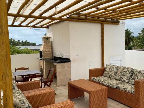 a patio with a couch and a table and a fireplace at Flats Marina Maragogi in Maragogi