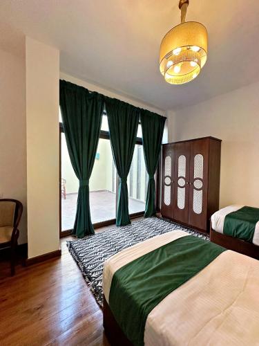 a bedroom with two beds with green curtains and a chandelier at Villa Mango Hotel, near the American University in Cairo, AUC, New Cairo in Cairo
