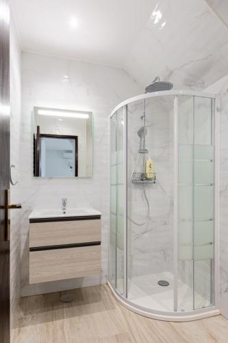 a bathroom with a shower with a sink and a mirror at Estúdio 24 em Santa Bárbara de Nexe - Faro in Colmeal