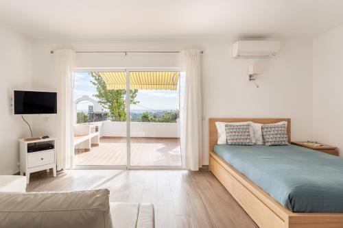 a bedroom with a bed and a view of a balcony at Estúdio 24 em Santa Bárbara de Nexe - Faro in Colmeal