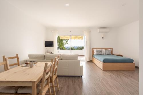 a living room with a bed a table and a couch at Estúdio 24 em Santa Bárbara de Nexe - Faro in Colmeal