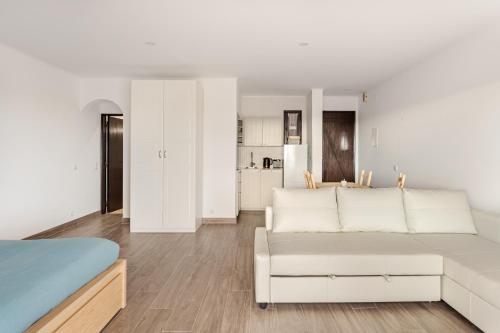 a white living room with a couch and a table at Estúdio 24 em Santa Bárbara de Nexe - Faro in Colmeal
