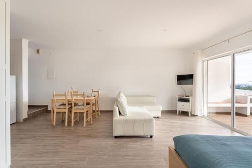 a white living room with a table and a chair at Estúdio 24 em Santa Bárbara de Nexe - Faro in Colmeal
