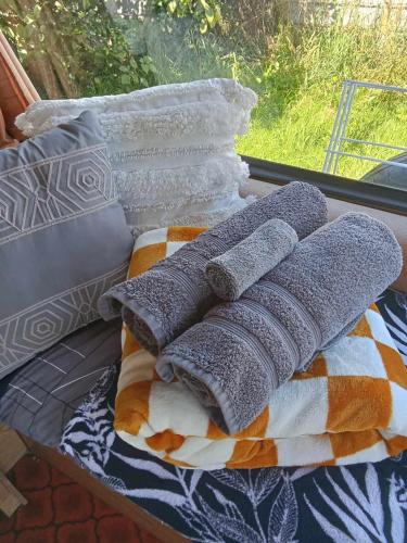 a pile of pillows sitting on a bed next to a window at Blissful Rental Caravan hire and Bnb in Motueka