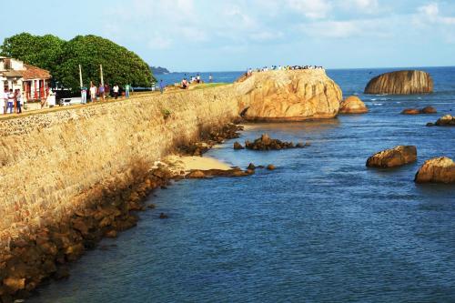 a group of people standing on a wall near the water at Orchard House Galle in Galle