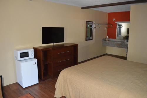 a bedroom with a bed and a tv and a microwave at Sun Down Lodge in Locust Grove