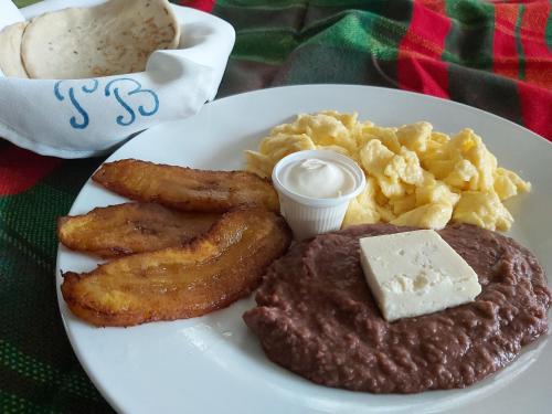 a plate of breakfast food with meat and potatoes andiments at Hotel Playa Bonita Tela in Tela