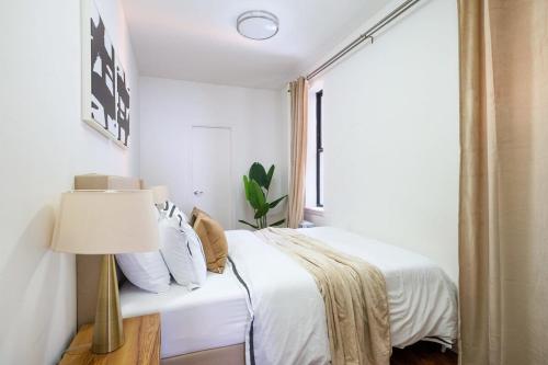 a bedroom with a bed with a lamp and a window at 1288-3RN New Renovated 1 Bedroom in UES in New York