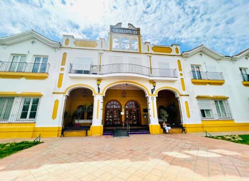 a large white building with yellow trim at Puente del Rey, El Rocio Deluxe in El Rocío