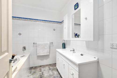 a white bathroom with a sink and a mirror at Beachside Retreat in Altona