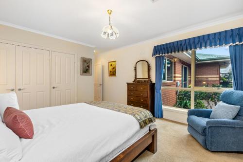 a bedroom with a bed and a chair and a window at Beachside Retreat in Altona