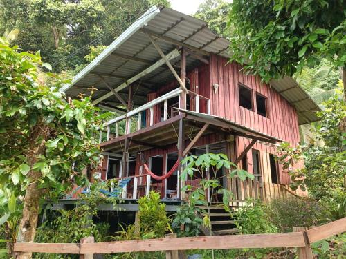 a red house with a porch and a wooden fence at Casa Origen in El Valle
