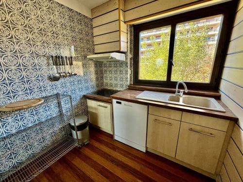 une petite cuisine avec un évier et une fenêtre dans l'établissement Appartement en front de mer au Lavandou avec vue panoramique - FR-1-816-16, au Lavandou