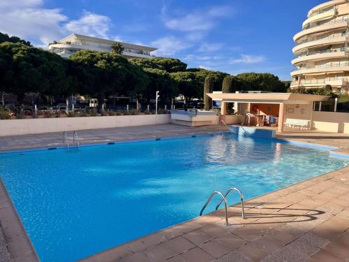 une grande piscine bleue avec un bâtiment en arrière-plan dans l'établissement Appartement avec piscine et terrasse, proche plage, climatisé, garage à Fréjus - FR-1-226A-184, à Fréjus