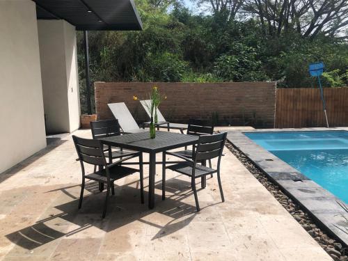 a black table and chairs next to a swimming pool at Casa NOGAL in Santa María del Oro