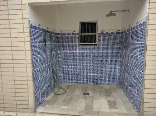 a blue tiled bathroom with a shower with a hose at Acolhedor com suíte e wi-fi in Praia Grande