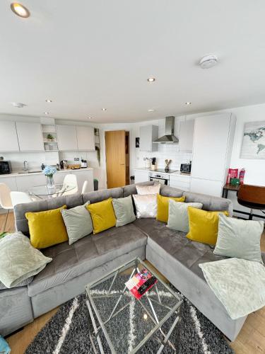 a living room with a gray couch with yellow pillows at Luxury Penthouse with Private Hot Tub Overlooking Leeds City Centre in Leeds