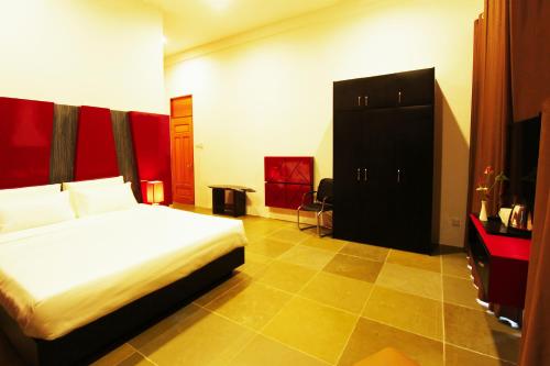a bedroom with a white bed and a black cabinet at Harmony Valley Retreat in Bukit Tinggi