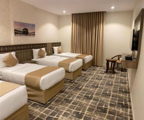 ein Hotelzimmer mit drei Betten und einem Fernseher in der Unterkunft ATYAF ALKHIR HOTEl in Mekka
