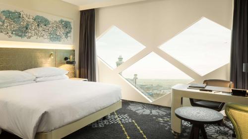 a hotel room with a bed and a desk and a window at Hilton Amsterdam Airport Schiphol in Schiphol