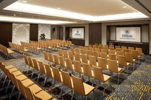a room with rows of chairs and a screen at Hilton Amsterdam Airport Schiphol in Schiphol