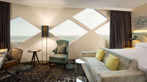 a hotel room with a bed and a couch and a window at Hilton Amsterdam Airport Schiphol in Schiphol