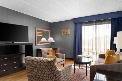 a living room with a couch and chairs and a television at DoubleTree by Hilton Bradley International Airport in Windsor Locks
