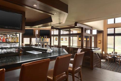 a bar in a restaurant with chairs and a television at DoubleTree by Hilton Bradley International Airport in Windsor Locks