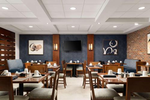 a dining room with tables and chairs and a tv at DoubleTree by Hilton Bradley International Airport in Windsor Locks