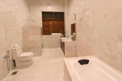 a bathroom with a tub and a toilet and a sink at Harmony Valley Retreat in Bukit Tinggi