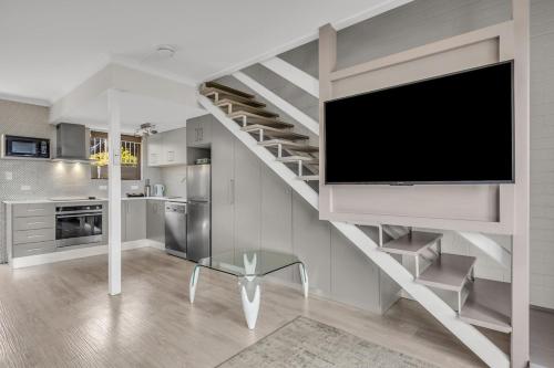 a living room with a staircase with a flat screen tv at Hydra Holiday Unit 3 in Merimbula