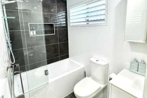 a white bathroom with a toilet and a shower at Coastal Modern 3 Bedroom Townhouse in Noosaville